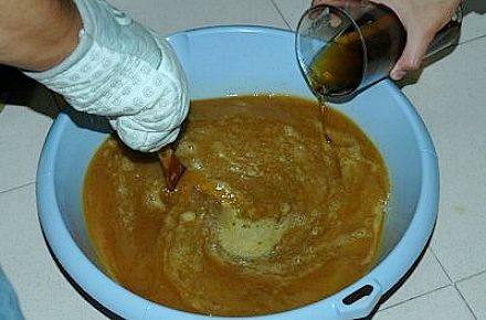 Tradiciones hacer jabón, poniendo aceite. Tradiciones hacer jabón casero, añadiendo aceite.